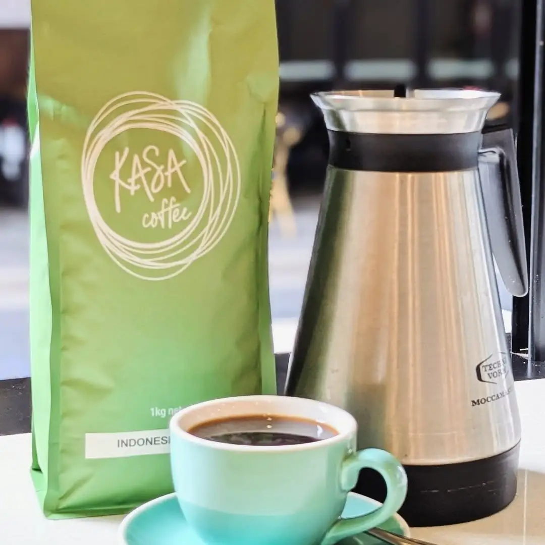 A bag of Kasa Coffee beans beside an espresso in a mint cup.