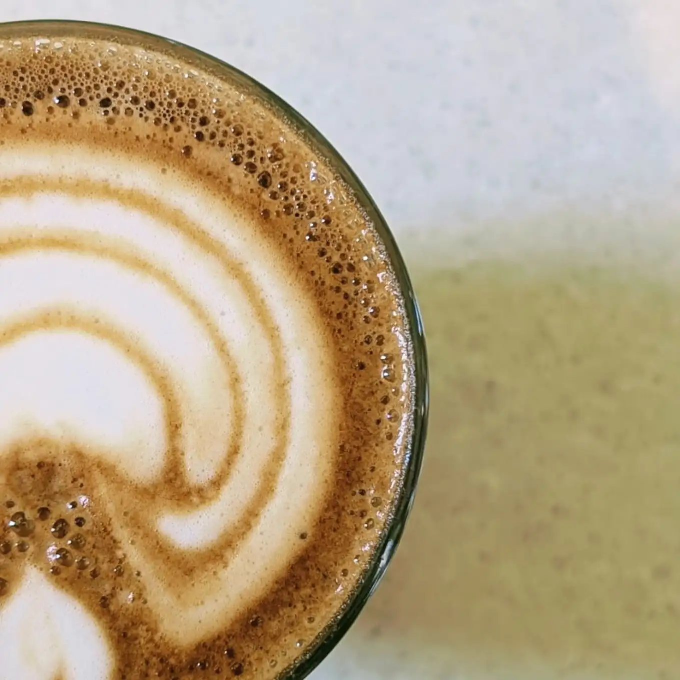 Latte art close up, a rosetta in a mint green cup.